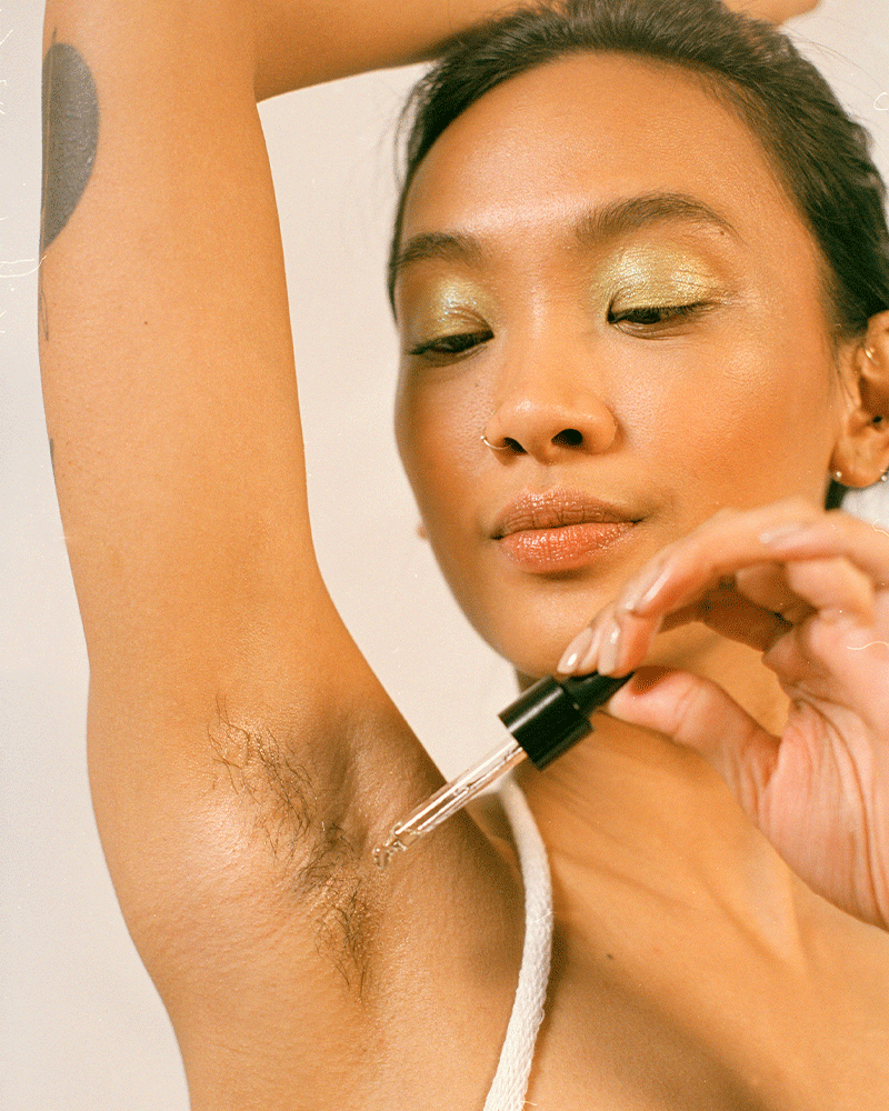 Woman in green eyeshadow applying Fur Oil to her underarm hair.