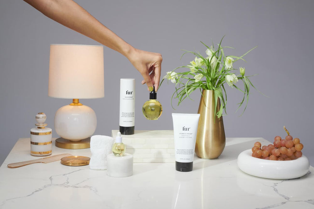 Image of hand holding Fur oil above table with other Fur products