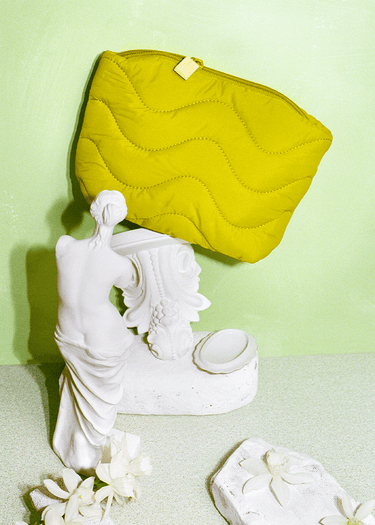 Fur chartreuse quilted dopp kit on mini statue.